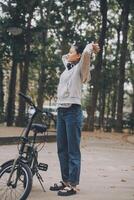 contento asiático joven mujer caminar y paseo bicicleta en parque, calle ciudad su sonriente utilizando bicicleta de transporte, eco amigable, personas estilo de vida concepto. foto