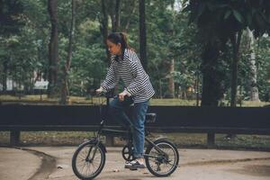 Happy Asian young woman walk and ride bicycle in park, street city her smiling using bike of transportation, ECO friendly, People lifestyle concept. photo