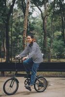 Happy Asian young woman walk and ride bicycle in park, street city her smiling using bike of transportation, ECO friendly, People lifestyle concept. photo