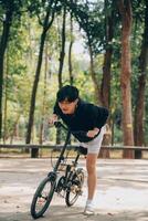 hermoso contento joven hombre con bicicleta en un ciudad calle, activo estilo de vida, personas concepto foto