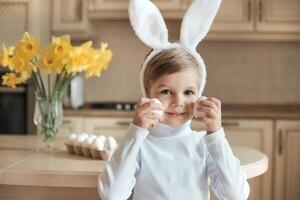 adorable niño en gracioso conejito orejas jugar con pollo huevos y Listo para Pascua de Resurrección día foto