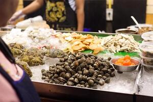 Fresh crab , shell , oysters , squid seafood on ice selling in a market photo