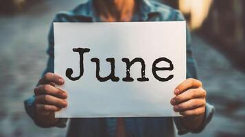 AI generated Hello June. Closeup of a woman holding a card with the word Hello June in her hands photo