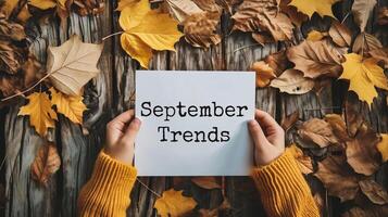 AI generated top view of woman holding card with september trends lettering on wooden background photo