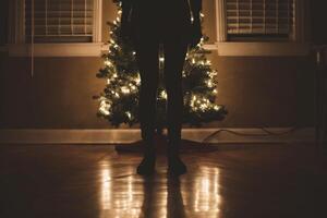 ai generado silueta de un niña en un habitación con un Navidad árbol foto