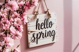 AI generated Hello Spring message on wooden sign hanging on pink wall with cherry blossoms photo