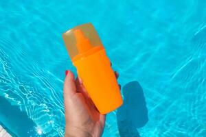 Spray sunscreen stands on the background of the pool photo