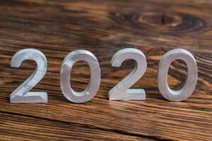 un número 2020 con blanco metal dígitos en oscuro marrón madera antecedentes con selectivo atención foto