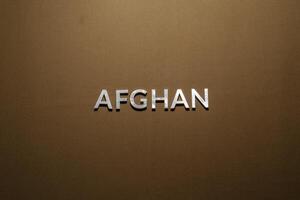 la palabra afgano colocada con letras de metal plateado sobre una tela de lona caqui tostada foto
