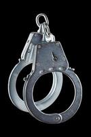 real zinc plated steel police handcuffs closed, isolated on black background photo