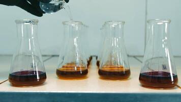 Scientific research laboratory where chemicals are mixed in flasks. The researcher adds several drops of the solution to the test tube. video