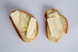 dos piezas de blanco un pan con mantequilla en blanco antecedentes foto