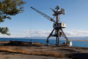 antiguo abandonado Soviético grua en Puerto balykchi en issyk-kul lago a soleado otoño tarde foto