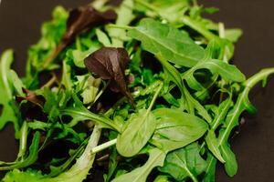 Mix of lettuce leaves different types on black table. photo