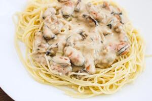 spaghetti with mussels in a creamy sauce on a plate photo