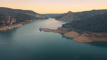 la Pesquera römisch heiter Dämmerung Über ein still Reservoir, Ruhe Reservoir flankiert durch bewaldet Klippen während Dämmerung, Gießen ein friedlich Ambiente. video