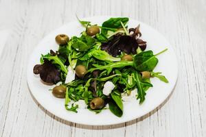 Salad leaves with arugula, cheese, green olives in a plate, healthy diet salad. photo