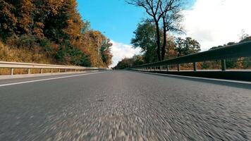 Aussicht von das Stoßstange von ein Auto Fahren auf ein Asphalt Straße beim hoch Geschwindigkeit im schleppend Bewegung. video