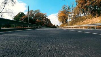 View from the rear bumper of the car to the road. Rear view of the car. A trip by car driving along an asphalt road through an autumn forest video