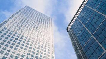 Bottom view of modern multi-storey buildings on background of blue sky. Action. Simple architecture of modern residential high rises with glass design reflecting blue sky video