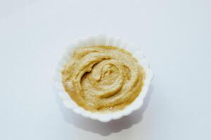 Mustard sauce in a white bowl on a white table. photo