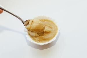 Mustard sauce in a white bowl on a white table. photo