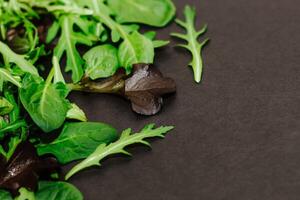 Mix of lettuce leaves different types on black table. photo