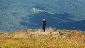 seul promeneur admiratif Montagne paysage, une solitaire figure des stands contemplant le vaste beauté de le montagneux terrain. video