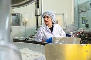 causa mujer trabajando en un comida fábrica vistiendo protector ropa y guantes. foto