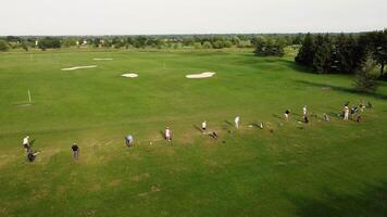 antenn se av golfare på frodig kurs, golf spelare spridd på en grön fält njuter en solig dag på de golf kurs. video