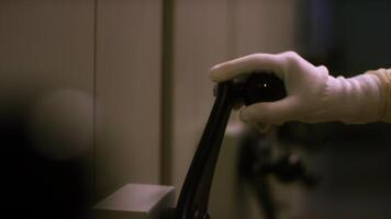 Close-up view of hand in white protective glove turning the large black handle of some metal box or storage. Stock footage. Vault door handle and dial video