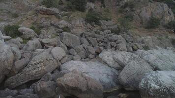 el costa de el bahía en el blanco mar de cerca ver de grande blanco y gris piedras cerca el montaña Pendiente y pequeño corriente o montaña río. disparo. rocoso lado de un acantilado cerca agua video