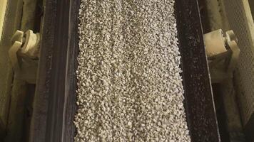 Close up of conveyor belt with gravel. Stock footage. Many small crushed stones on the production line at the construction materials production factory, heavy industry concept. video