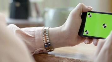 Close-up of female hands holding phone horizontal with green screen. Stock footage. Female freelancer working with phone tapping on green screen video