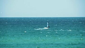 Visão do a homem em uma windsurf pegando a vento em mar água contra a azul Claro céu. tomada. verão recorrer video