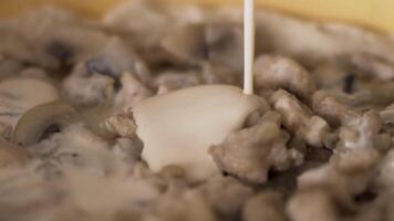 Close up of pan with mushrooms in a cream sauce. Action. Thick cream being poured into the pan with fried champignons, preparation of mushroom sauce. video