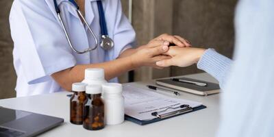 Doctor giving hope. Close up shot of young female physician leaning forward to smiling elderly lady patient holding her hand in palms. Woman caretaker in white coat supporting encouraging old person photo