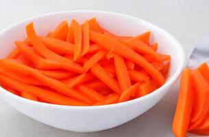 AI generated Sliced carrot in a bowl on white background photo