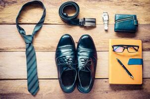 Leather shoes and accessories for work lay on the wooden floor photo