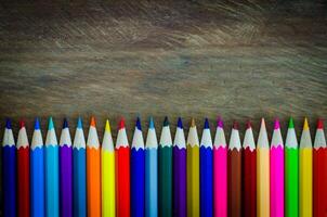 line of colored pencils on wood background photo
