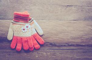 winter gloves orange color on wooden background - tone vintage photo