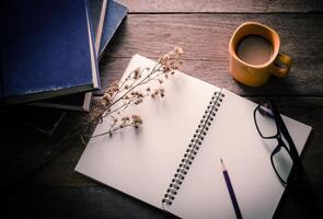 café taza con libros lente cuaderno y lápiz en el de madera mesa foto