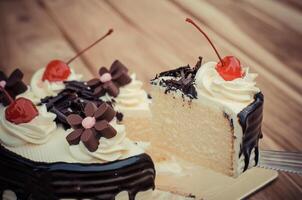 cumpleaños pastel, vainilla chocolate Cereza estaba dividido piezas en un de madera mesa. foto