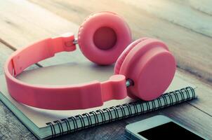 Earphone Pink put on notebooks and smartphones on wooden floor morning light photo