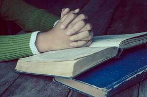 Hands with Bible on wood table photo