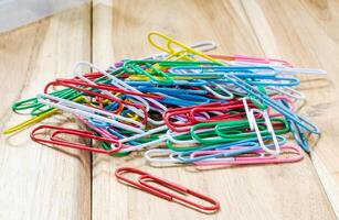 Colorful paper clips on a wooden table. photo