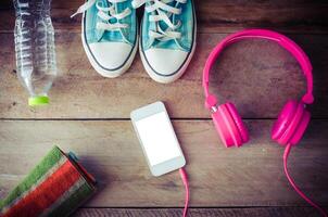 Shoes, water bottles headset smart phone scarf on a wooden table ready to depart. photo