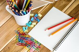 de colores lapices y cuaderno papel acortar pérdidas de balón en un de madera mesa. foto