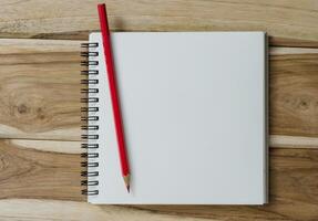 blank notebook with pencil on wooden table - still life photo