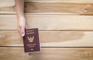 mano participación un Tailandia pasaporte en de madera antecedentes foto
